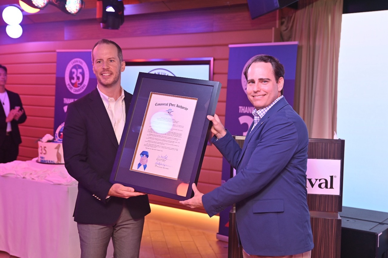David German, Port Canaveral’s VP of Cruise Business Development (left) presents a resolution from the Canaveral Port Authority Board of Commissioners to David Candib, Carnival’s VP of Port Operations, during a ceremony aboard Carnival Mardi Gras.